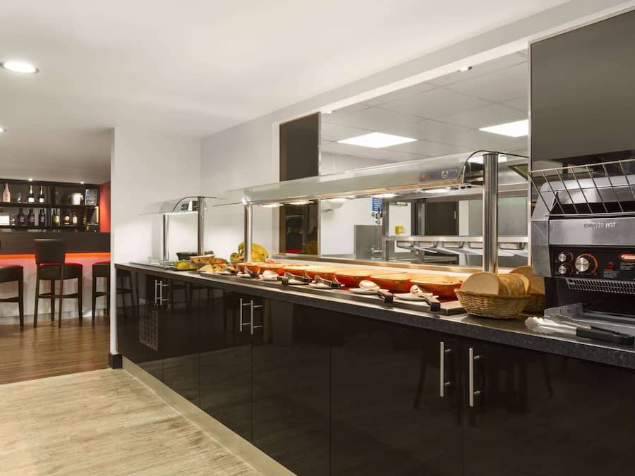 Eine moderne Küche mit langer Arbeitsfläche, Grillmöglichkeit und Barbereich mit Hockern.