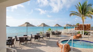 Relax by the pool with ocean views, surrounded by natural rock formations and shaded by umbrellas.