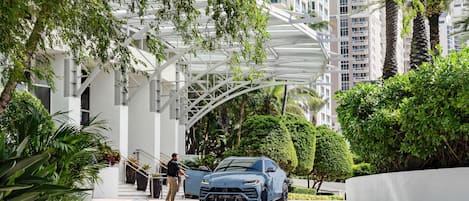 A modern building with a covered walkway and a blue car parked in front.