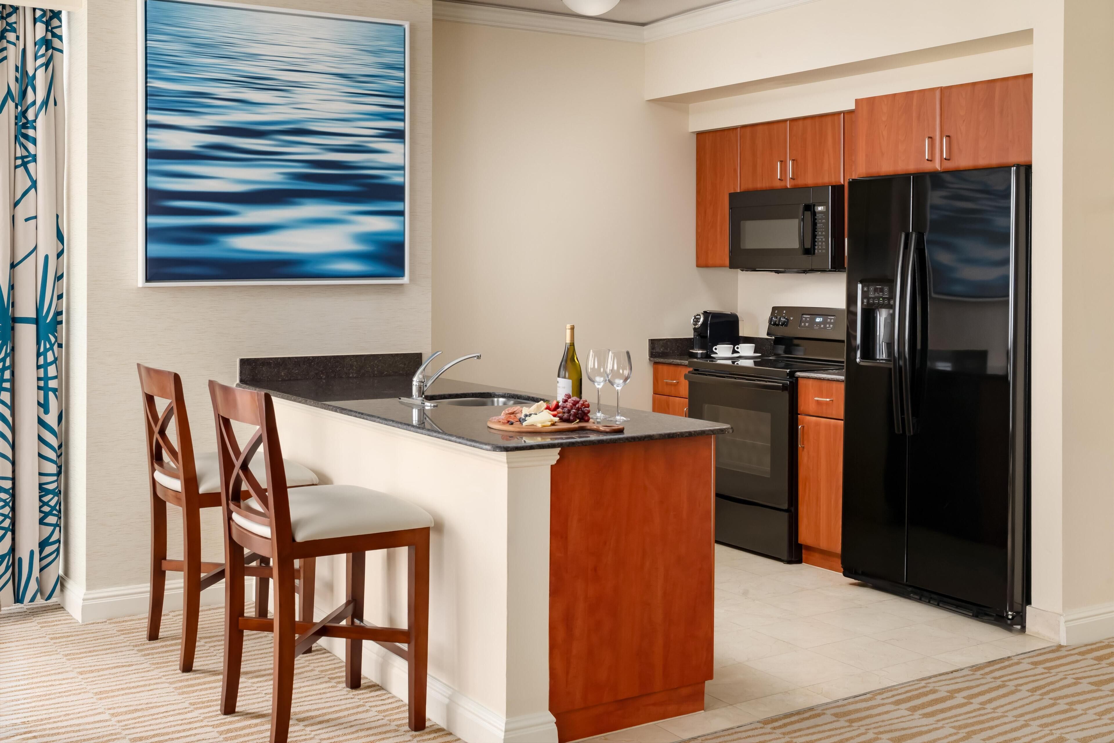 A modern kitchen with wooden cabinets, a black refrigerator, and a central island with seating.