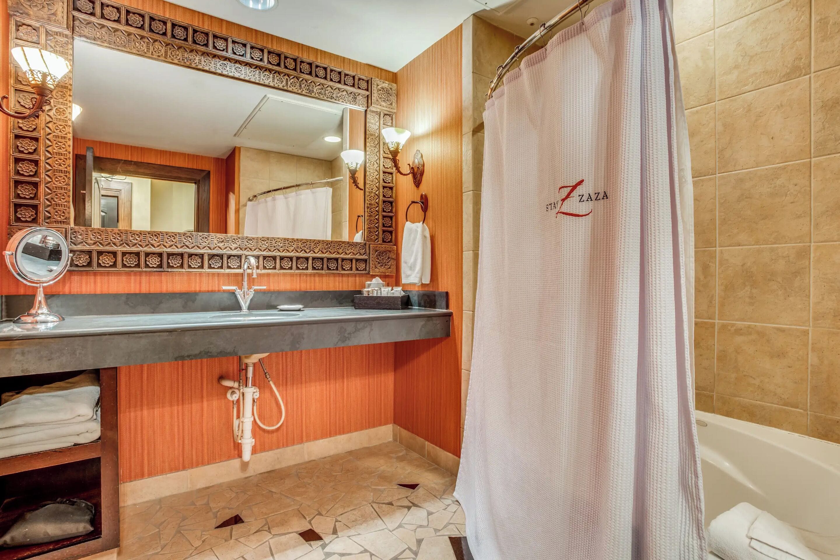 A bathroom with a shower curtain, a sink with a mirror, and a towel rack.
