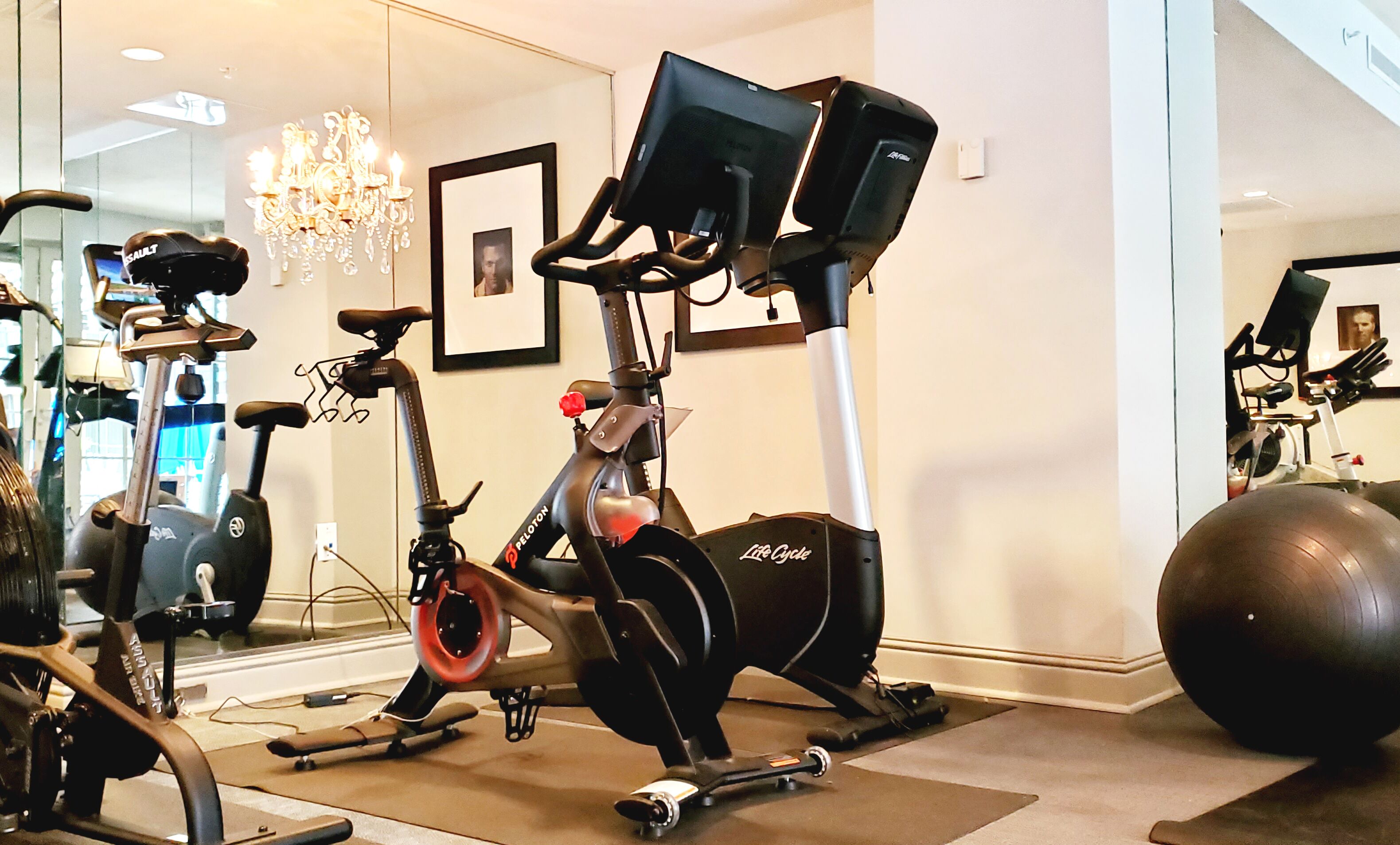 A home gym with an elliptical, a stationary bike, and a large exercise ball.