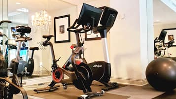A home gym with an elliptical, a stationary bike, and a large exercise ball.