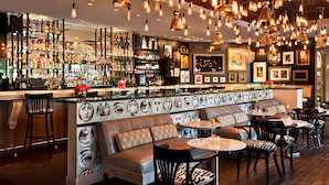 A bar area with a long counter, multiple seating options, and a variety of bottles and glasses on shelves. - Hotel ZaZa Dallas (Dallas)