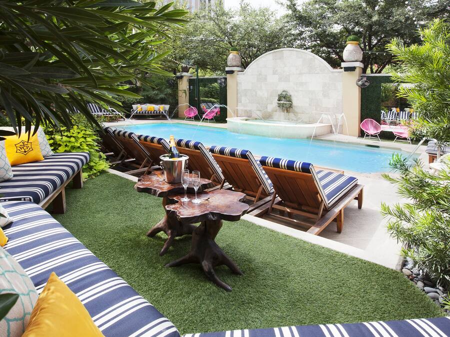 A poolside area with lounge chairs, a table with drinks, and a fountain.