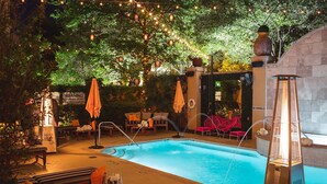 A pool area with lounge chairs and umbrellas, surrounded by greenery and string lights. - Hotel ZaZa Dallas (Dallas)