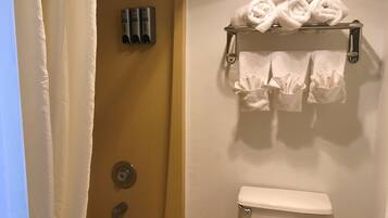 Un baño con inodoro, toallero con toallas, ducha y secador de manos.