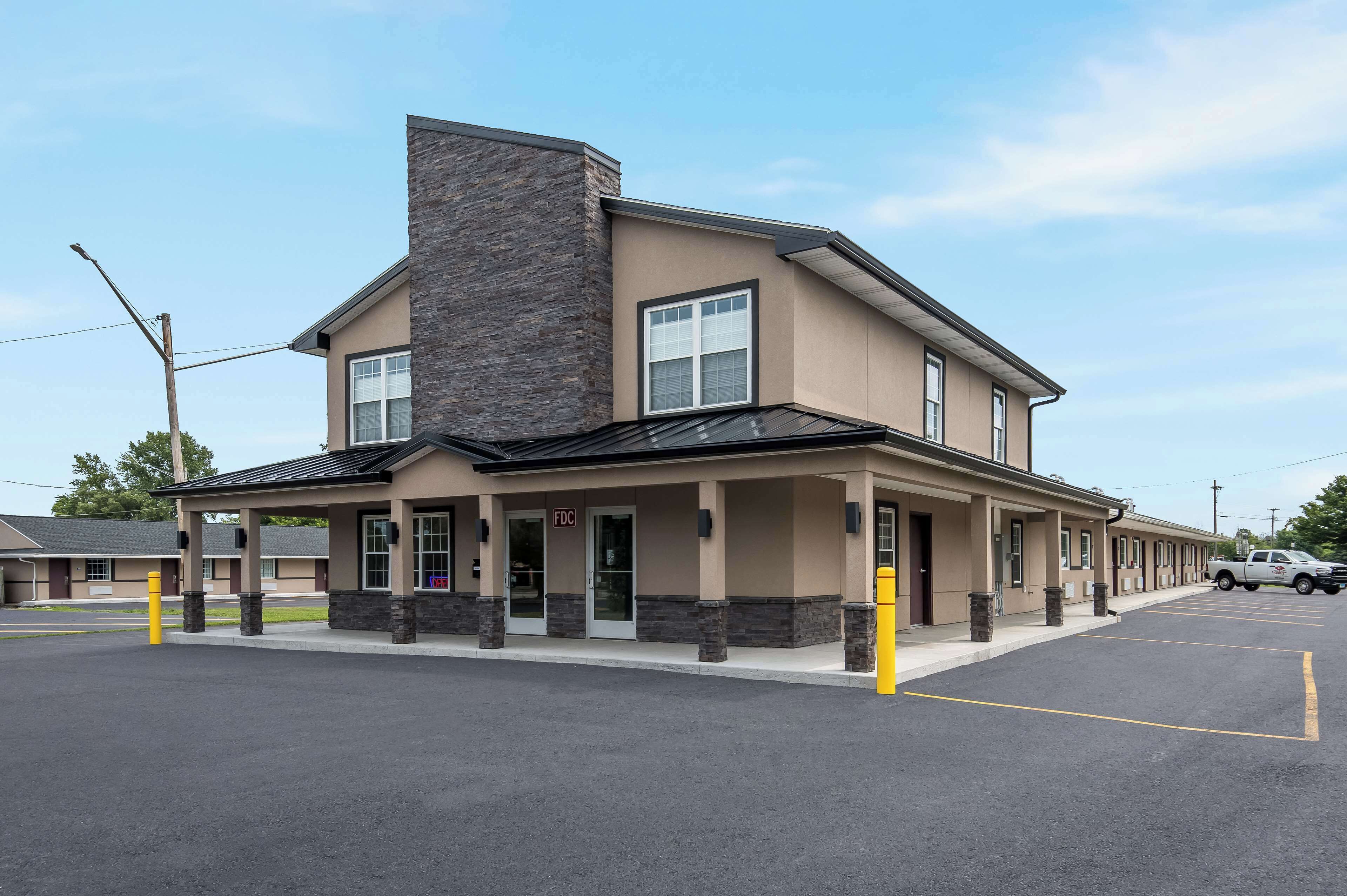 A two-story building with a beige facade and a stone accent wall, featuring a covered entrance and a parking lot.