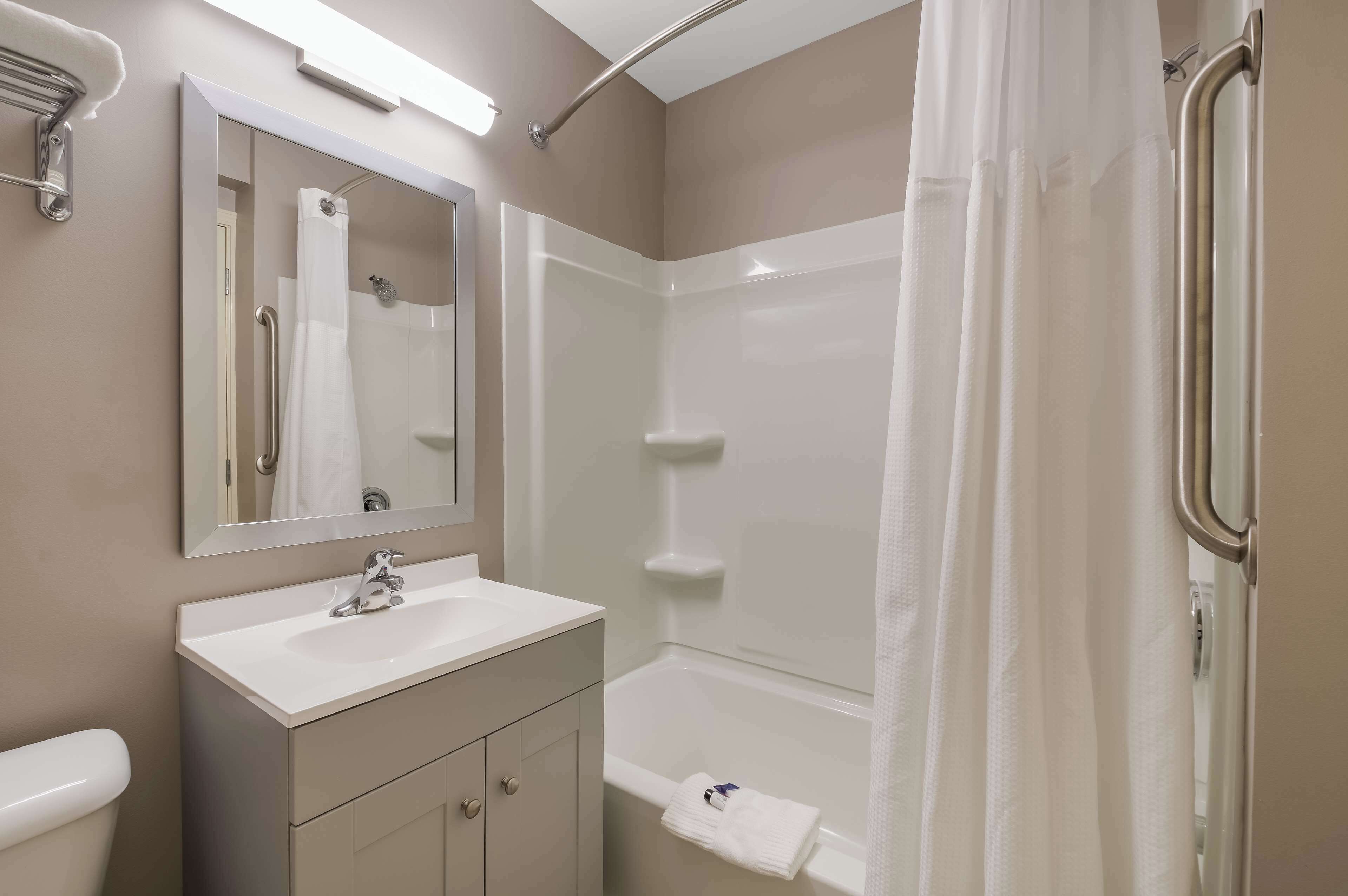 A modern bathroom with a white sink, mirror, and shower.