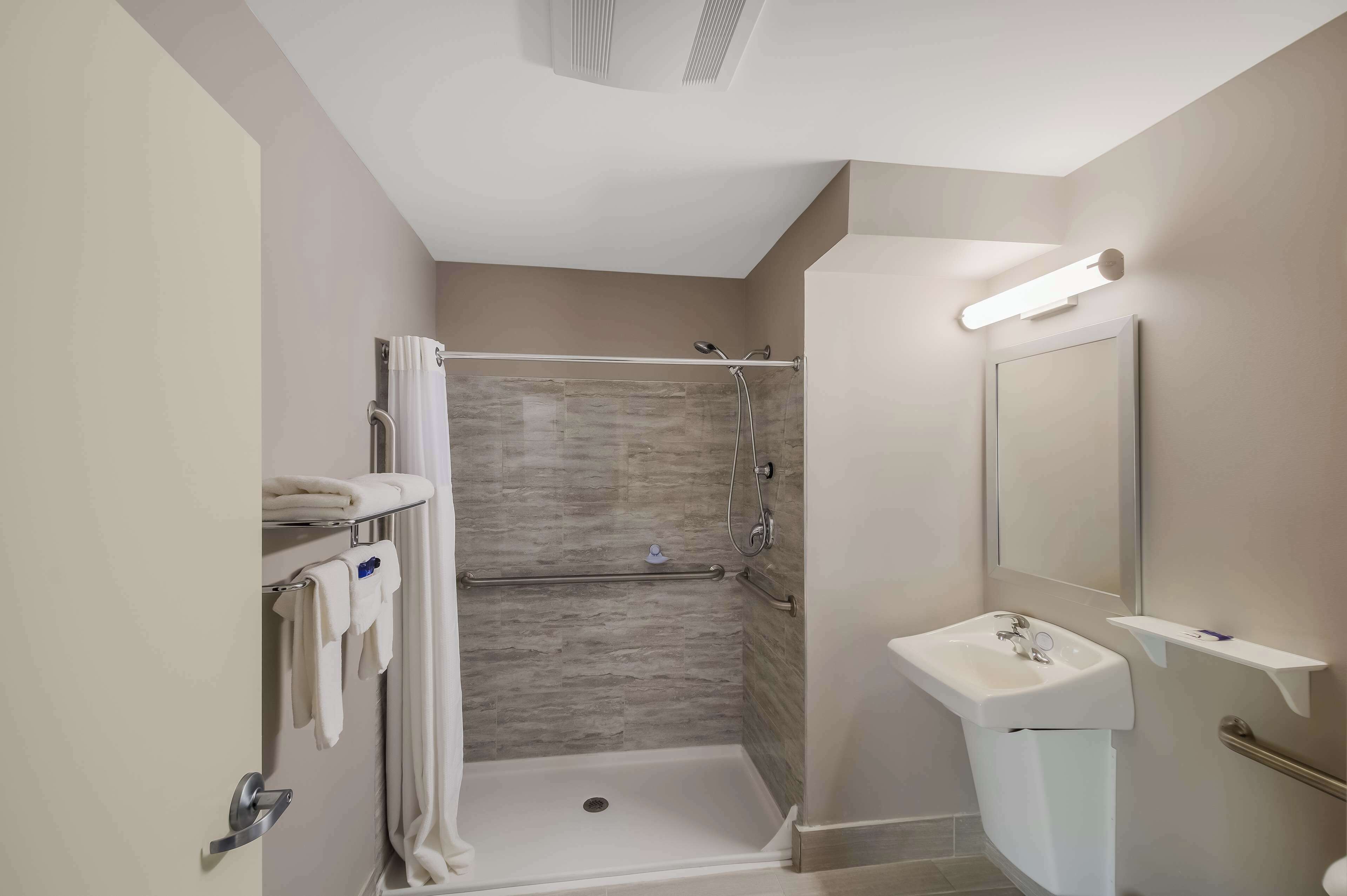 A modern bathroom with a walk-in shower, a sink, and a mirror.