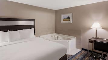 Habitació d'hotel amb un llit gran, un bany separat amb banyera i un escriptori amb cadira.