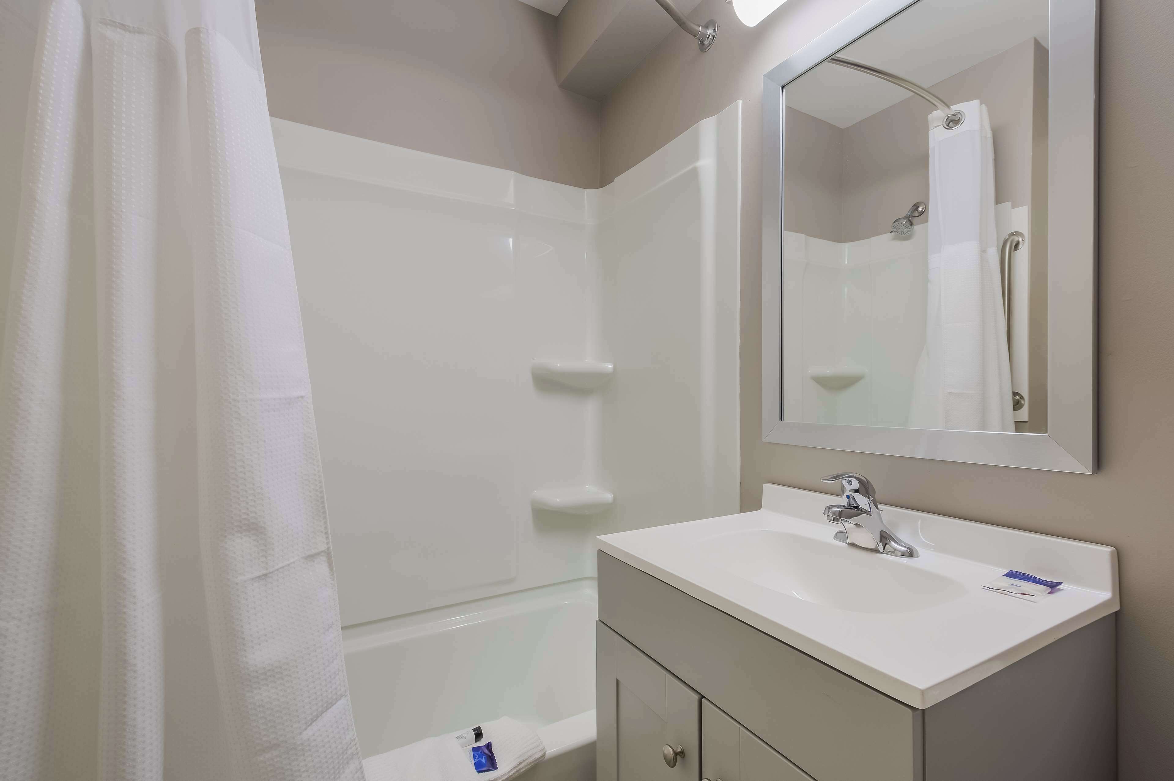 A bathroom with a white sink, mirror, and shower curtain.