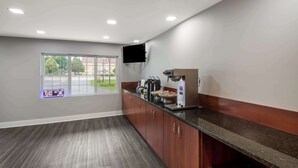 A modern kitchen with a large window, built-in cabinets, a flat-screen TV, and a coffee machine. - Americas Best Value Inn Farmington (Farmington)