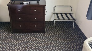 Een donker houten dressoir, een flatscreen televisie, een klein metalen stoeltje en een wandrek.
