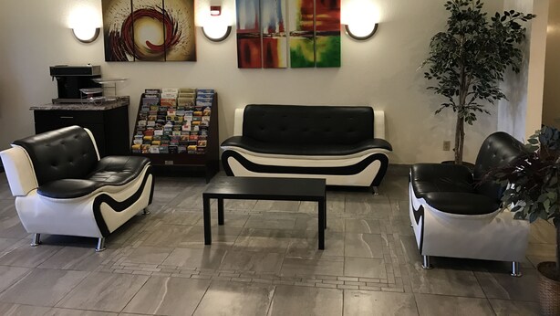 Een moderne woonkamer met een zwart-wit bank, een koffiezetapparaat, een tijdschriftenrek en een groot abstract schilderij.