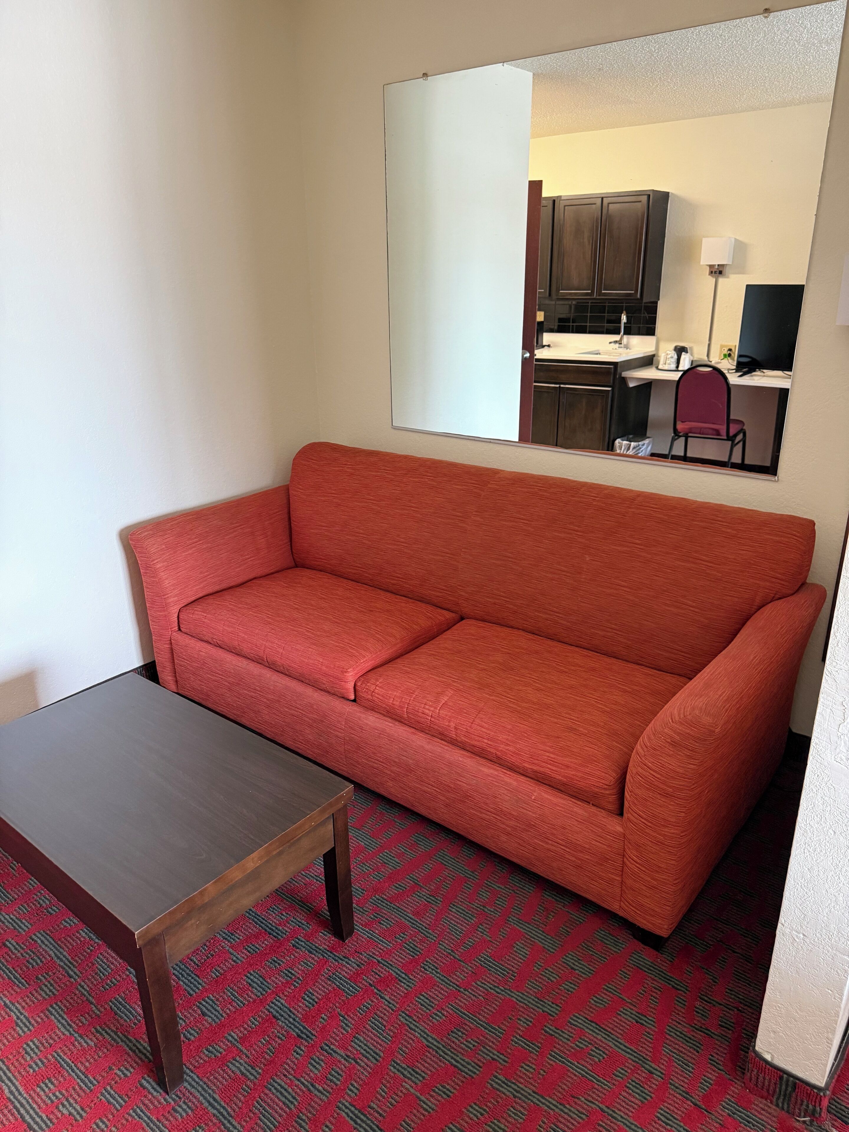 A room with a red sofa, a wooden table, and a patterned carpet.