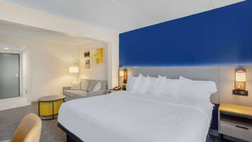 Ein Hotelzimmer mit einem großen Bett, einer Couch, einem kleinen Tisch und einem Schreibtisch mit einer Lampe.