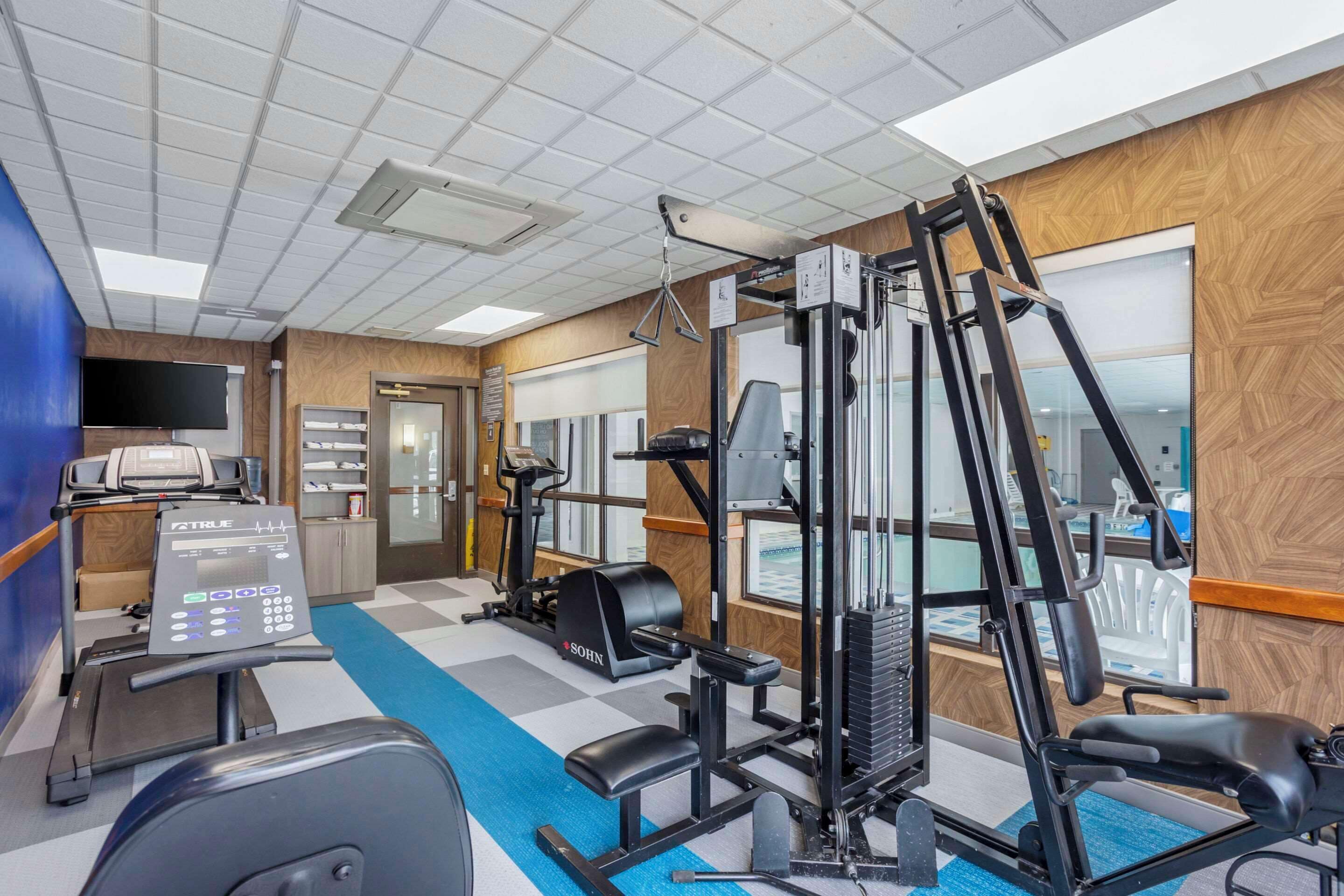 A gym with cardio equipment, weight machines, and a blue carpet.