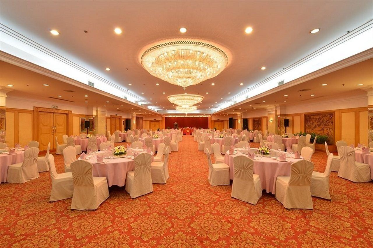 Una sala de banquetes amb taules rodones, cadirees i un gran candelabrum.