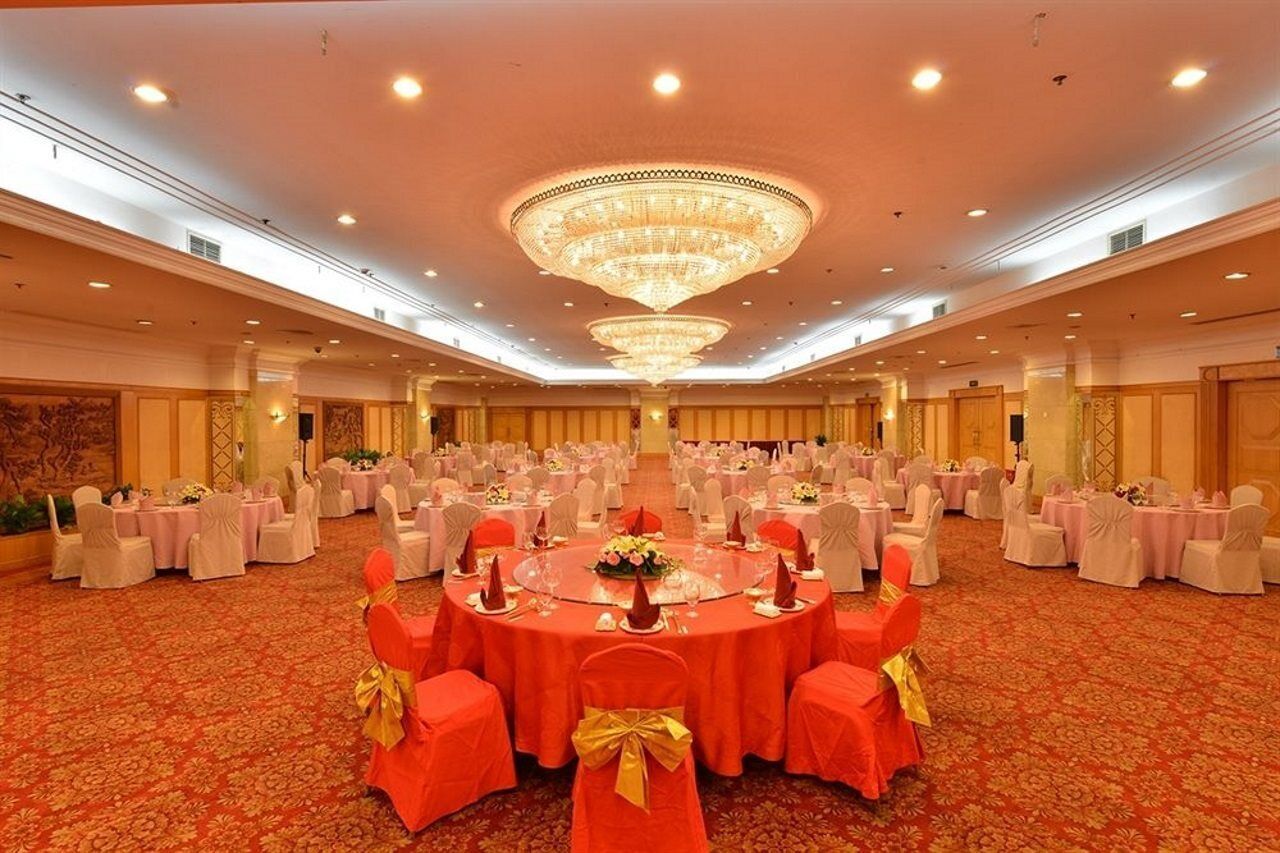 A banquet hall with round tables, chairs, and a large chandelier.