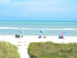 Perto da praia, areia branca, guarda-sóis 