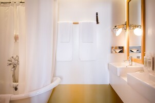 Ein modernes Badezimmer mit einer Badewanne, zwei Handtuchhaken, einem Waschbecken und einem beleuchteten Spiegel.