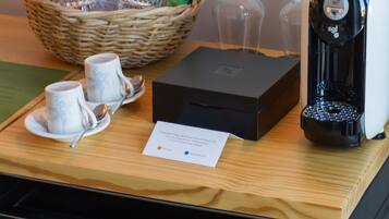 A breakfast setup with a basket of snacks, a coffee maker, and two cups on a tray.