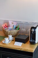Ein Frühstücksangebot mit einer Snackkorb, einer Kaffeemaschine und zwei Tassen auf einem Tablett.