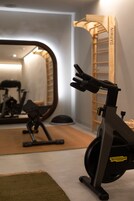Un gimnasio con una bicicleta estática, un espejo y una escalera de madera.