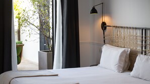 A neatly made bed with white linens, a black headboard, and a bedside lamp.