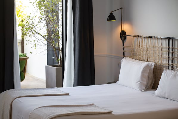 A neatly made bed with white linens, a black headboard, and a bedside lamp.