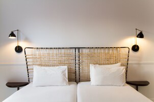A double bed with a woven headboard, two bedside tables, and wall-mounted lamps.
