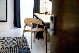 Ein modernes Zimmer mit einem Holzbstuhl, einem Schreibtisch und einem gemusterten Teppich.