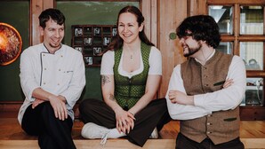 Three people sitting on a wooden bench in a room with wooden walls and a green chalkboard. - Hotel Prinzregent München (Munich)