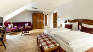 A bedroom with a large bed, a wooden bench, a sofa, and a desk with a chair. - Hotel Prinzregent München (Munich)