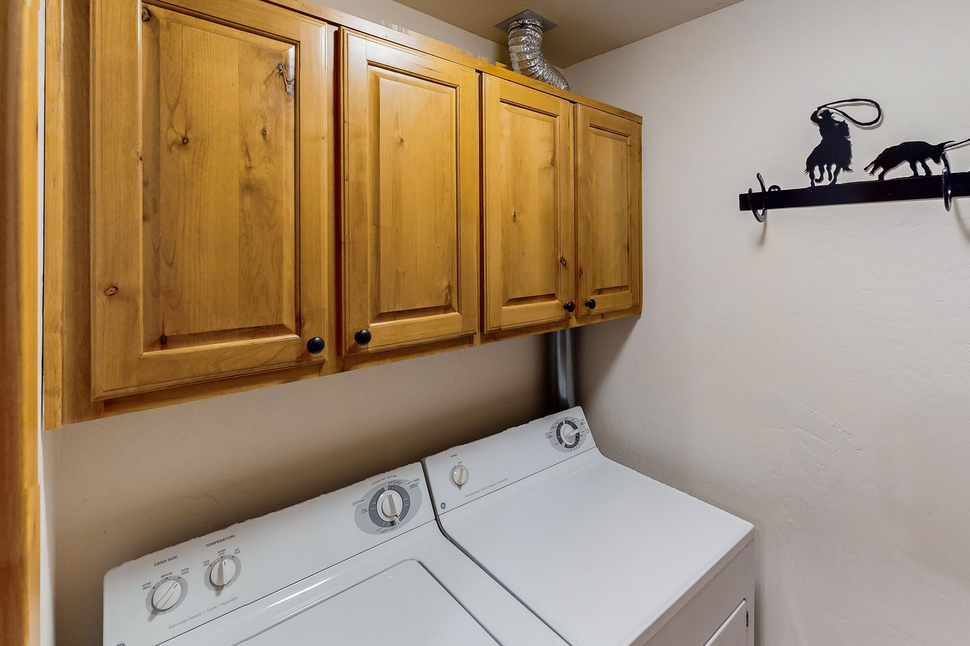 A laundry area with wooden cabinets and a white washer and dryer.