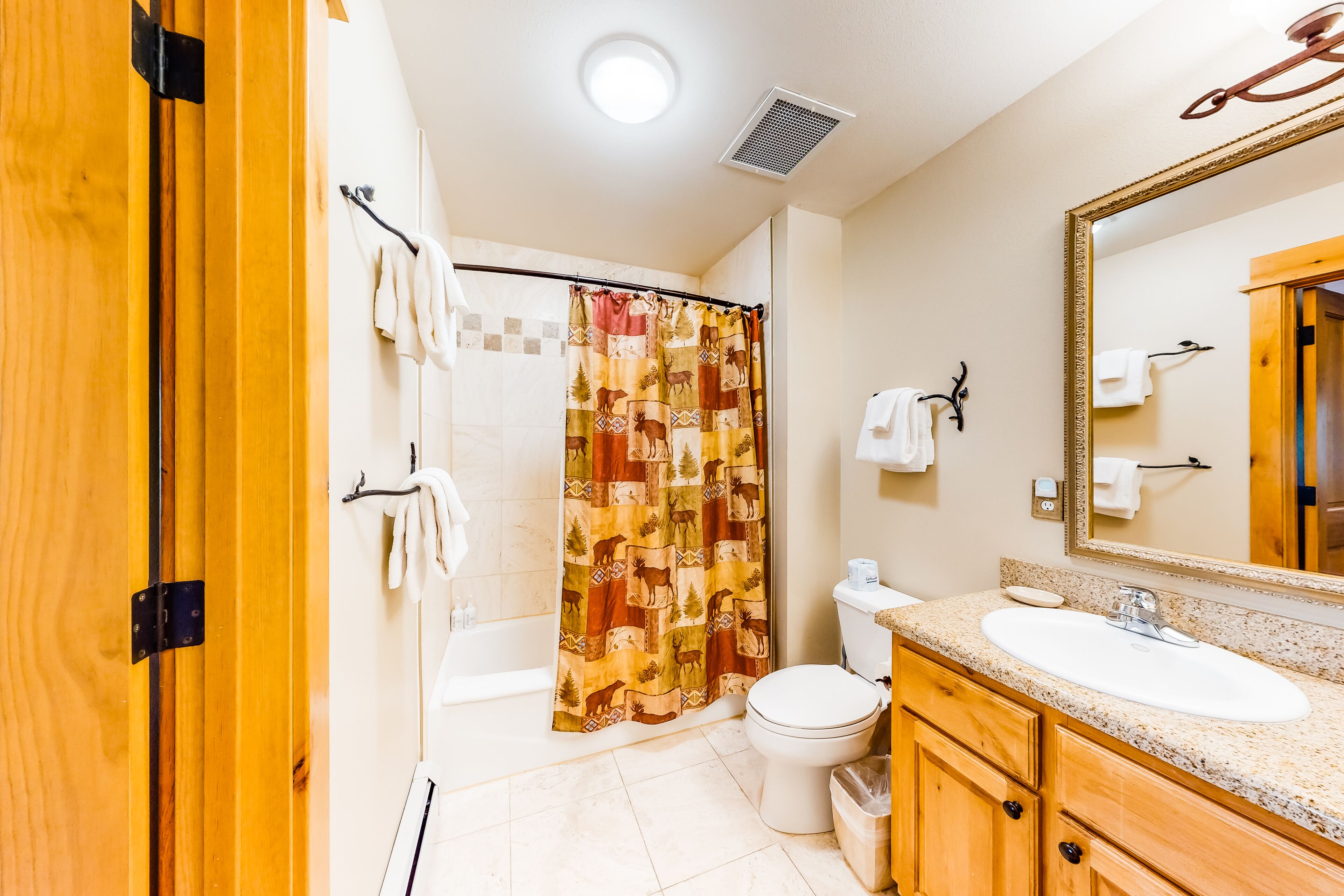 Un baño con ducha, inodoro, lavabo y armarios de madera.