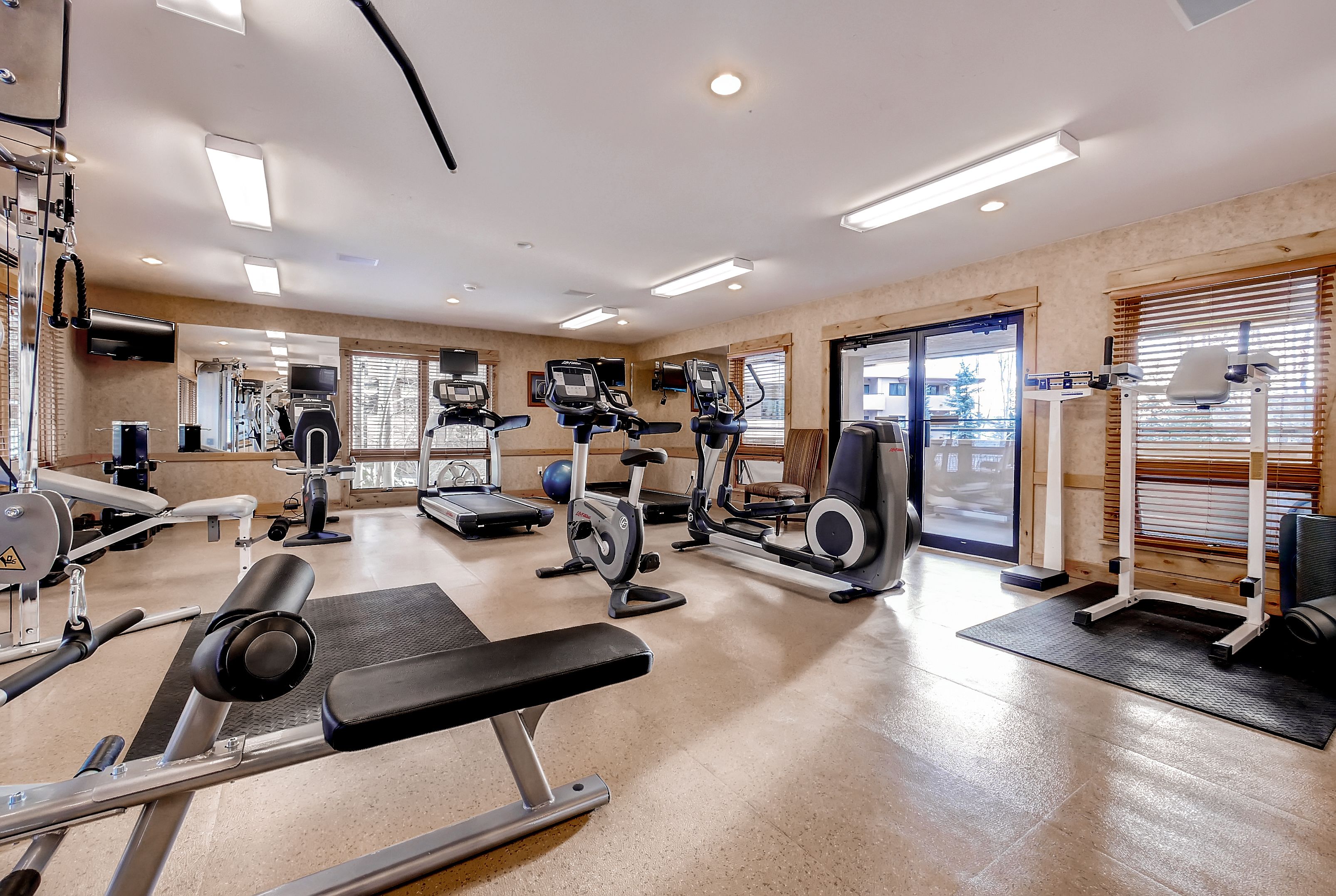 A gym with various exercise equipment, including treadmills, stationary bikes, and weight machines.
