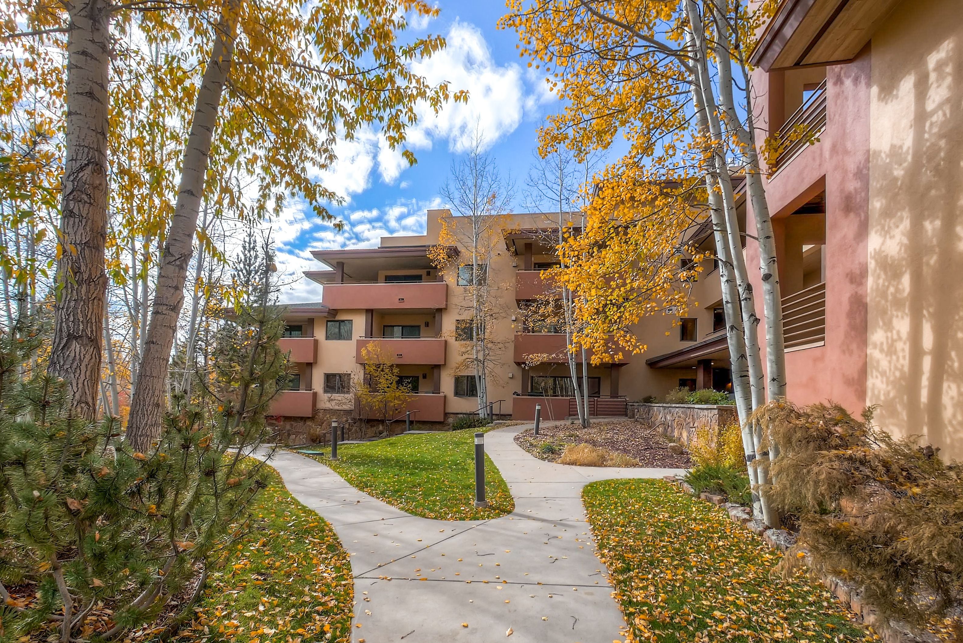 A multi-story building with a central courtyard surrounded by trees and a pathway.