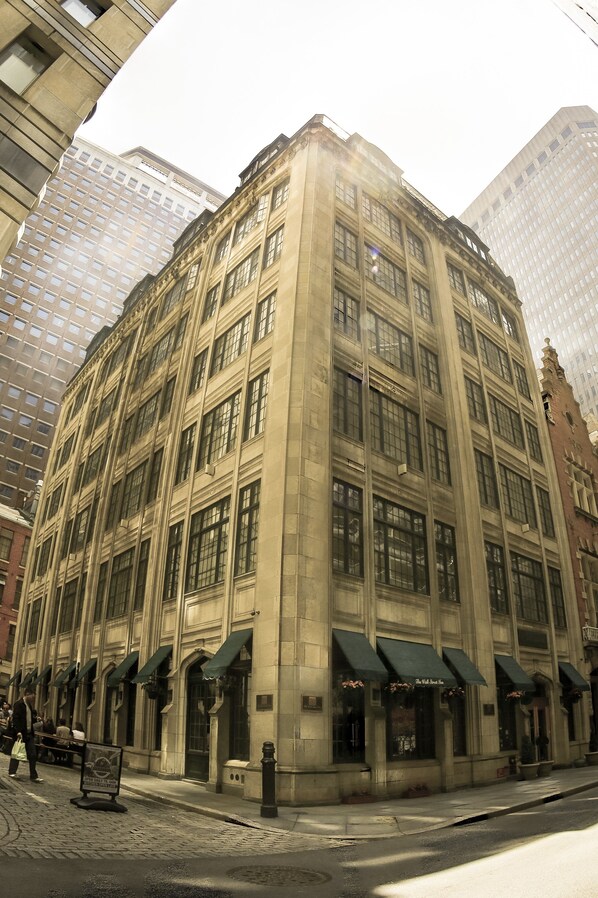 A historic building with a corner entrance, large windows, and a green awning. - The Wall Street Inn (New York)