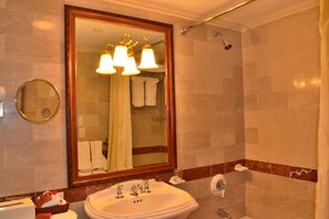 A bathroom with a large mirror, a sink, a shower, and a towel rack. - The Wall Street Inn (New York)