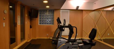 A gym with exercise equipment, a television, and a window with a view of the outside.