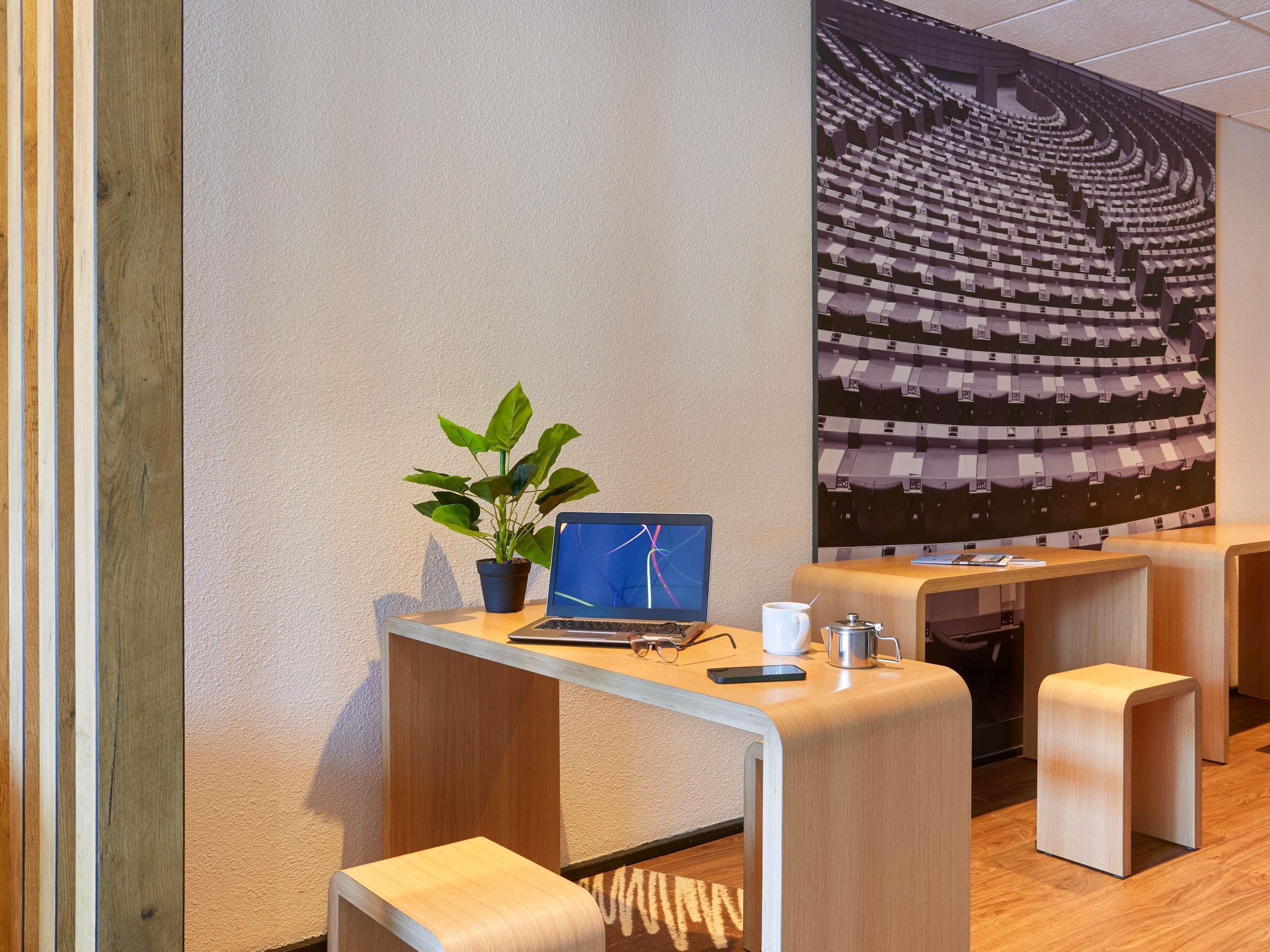 Un espace de bureau moderne avec un ordinateur portable, une plante en pot et une tasse de café sur un bureau en bois.