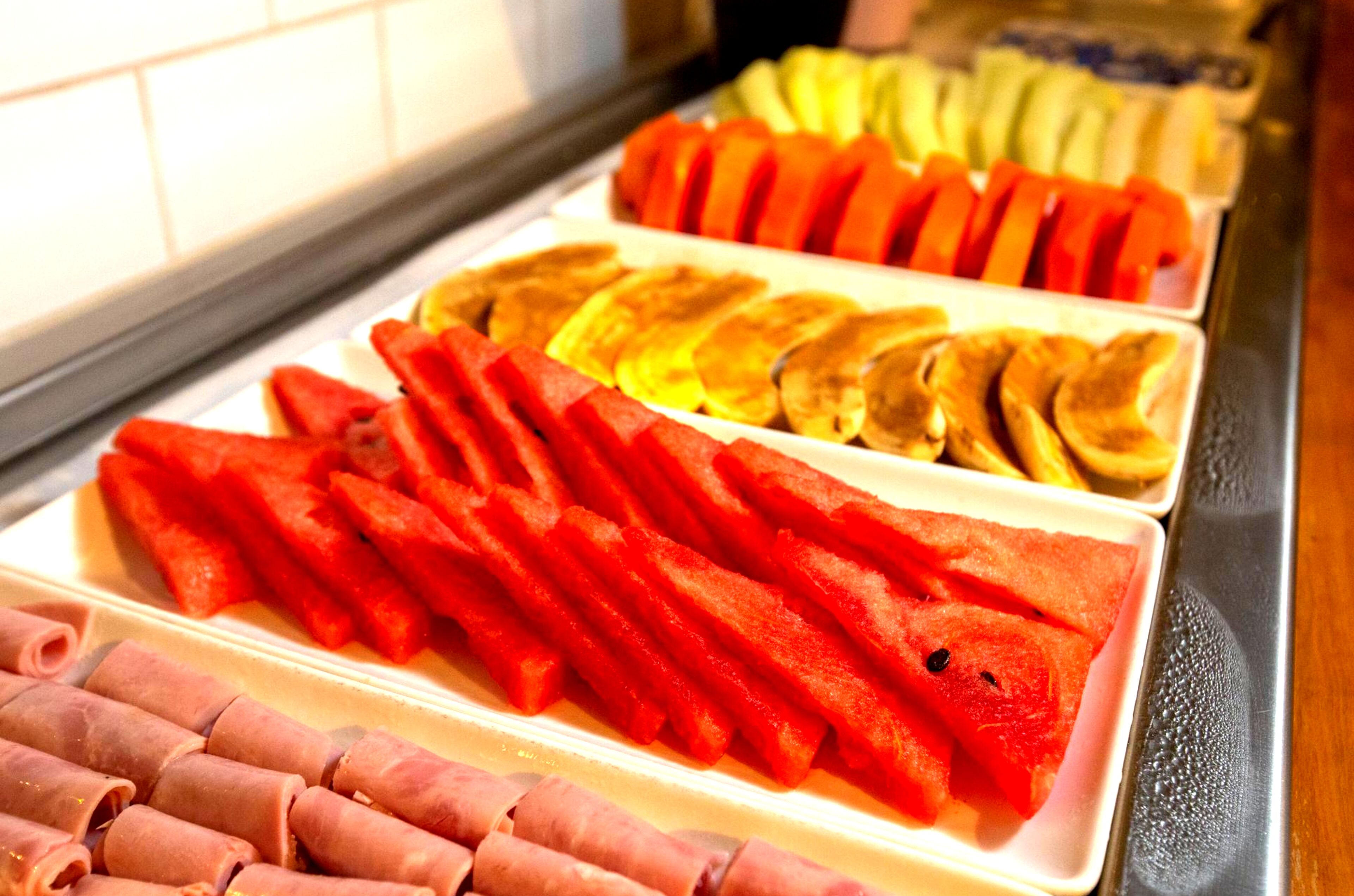 Una exhibición de frutas y verduras cortadas en una sección refrigerada.
