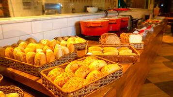 A buffet with various breads and pastries displayed in wicker baskets.