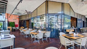 A restaurant with outdoor seating, wicker chairs, and a brick wall. - ibis Vitoria Praia Do Canto (Vitoria)