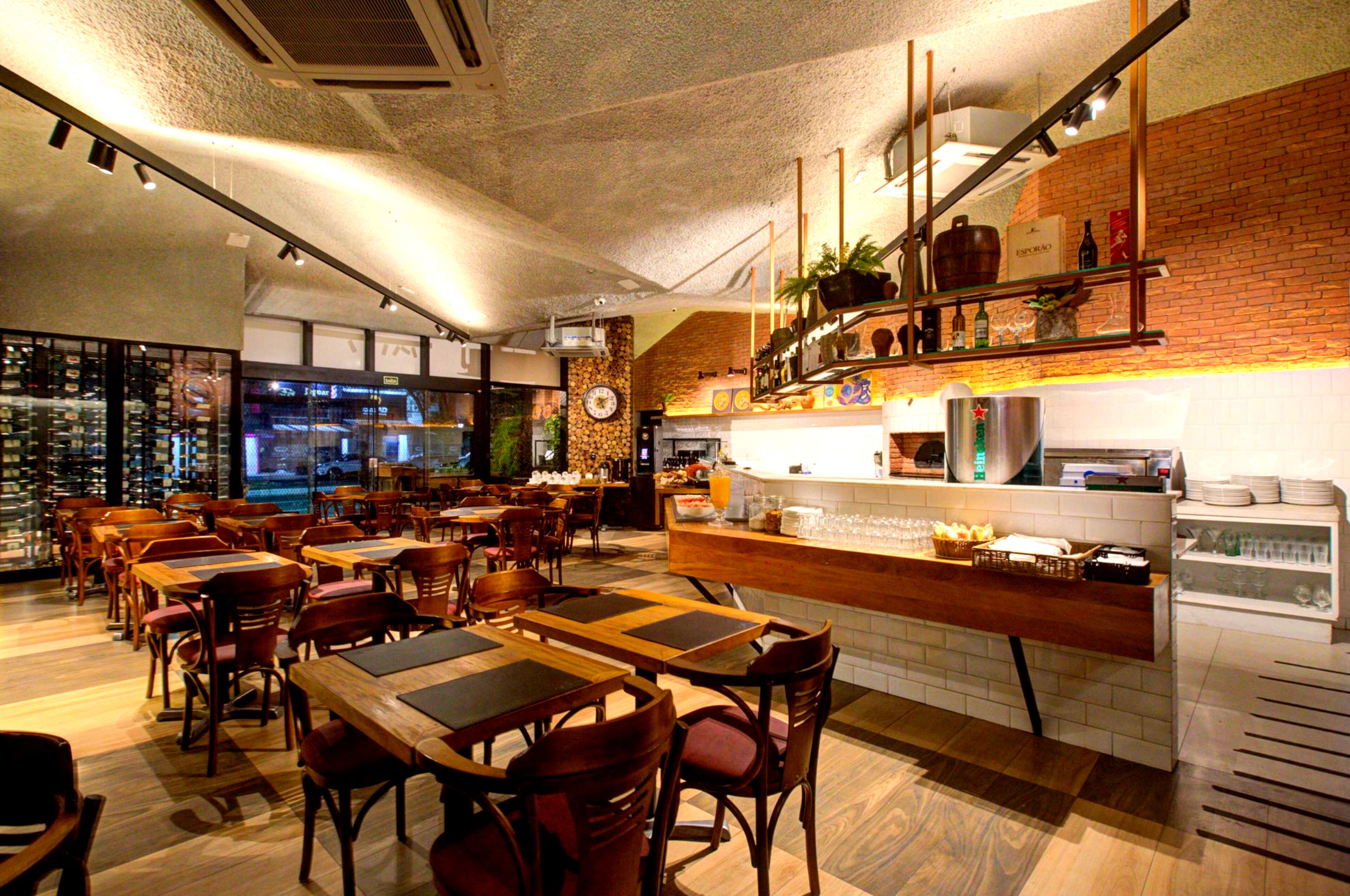 A restaurant with wooden tables and chairs, a counter with a cash register, and a brick wall.