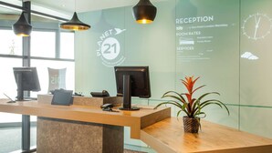 A reception desk with a digital screen, a plant, and pendant lighting. - ibis London Wembley (Wembley)