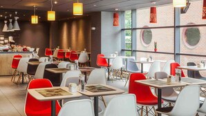 A modern restaurant with red and white chairs, tables with menus, and pendant lights. - ibis London Wembley (Wembley)