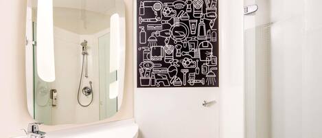 A modern bathroom with a white sink, a mirror, a toilet, and a shower.